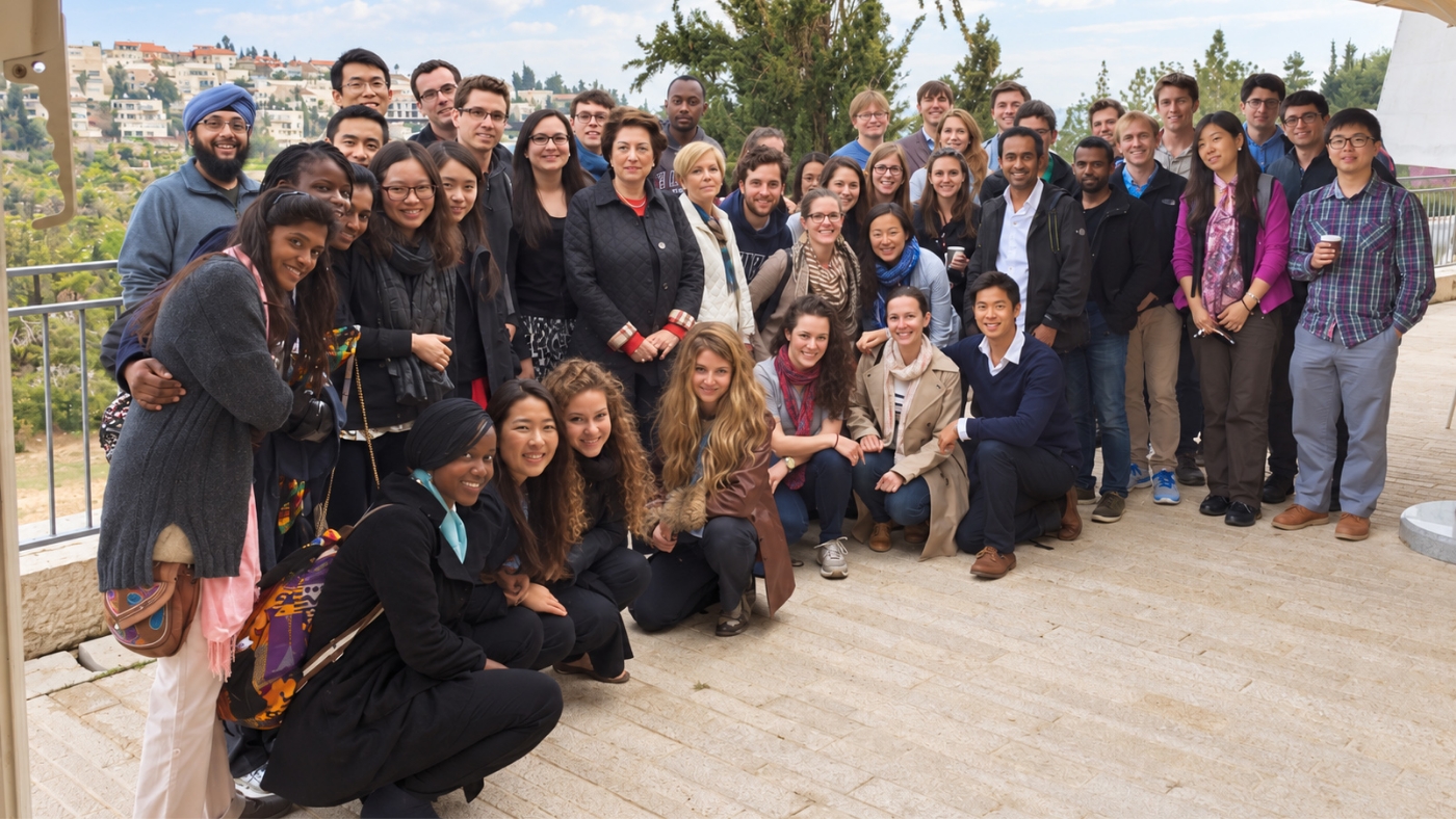 A large group of students and faculty posing together on an overlook in Israel